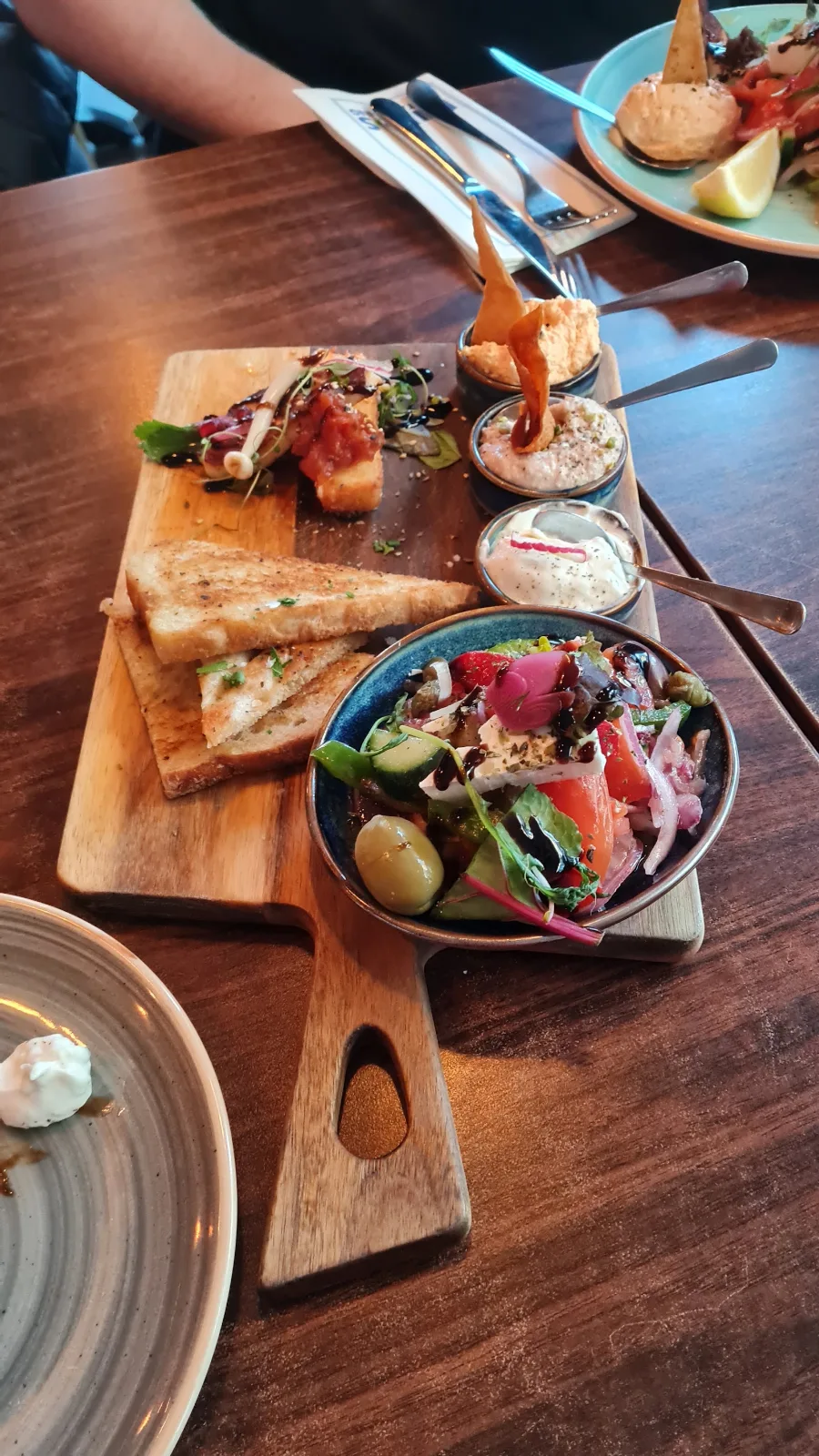 Förrättsplanka med vitlöksbröd, dippar och grekisk sallad
