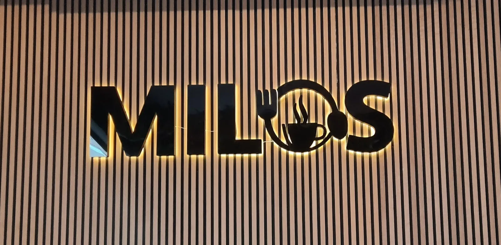 Milos logotyp med bakgrundsbelysning på trävägg i restaurangen