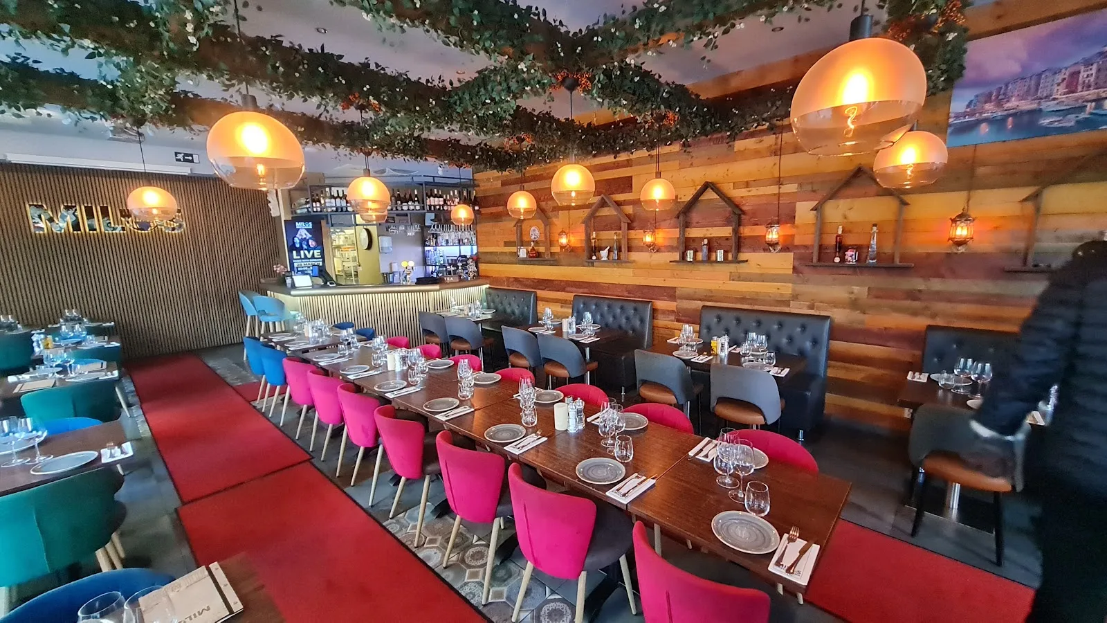 Matsalen på Milos Restaurang med dukade bord, rosa stolar och varm belysning
